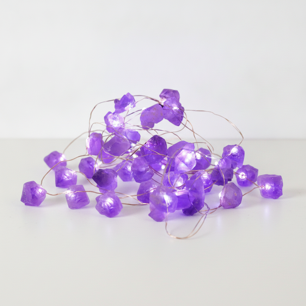 Amethyst crystal fairy lights on a clean white surface against a white wall