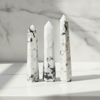 Rainbow moonstone six face obelisk on a marble table with a marble wall behind