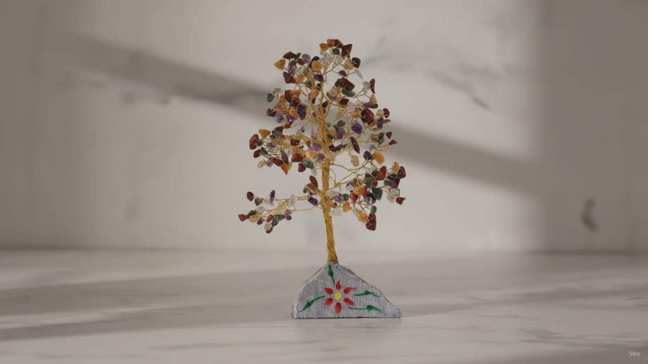 Large multi gemstone crystal tree on a marble table, sunlight moving across the wall