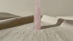 Rose quartz crystal obelisk point on linen, slow zoom in