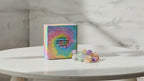 Mixed gemstone crystal fairy lights in their rainbow gift box on a marble table, sunlight moving across the wall