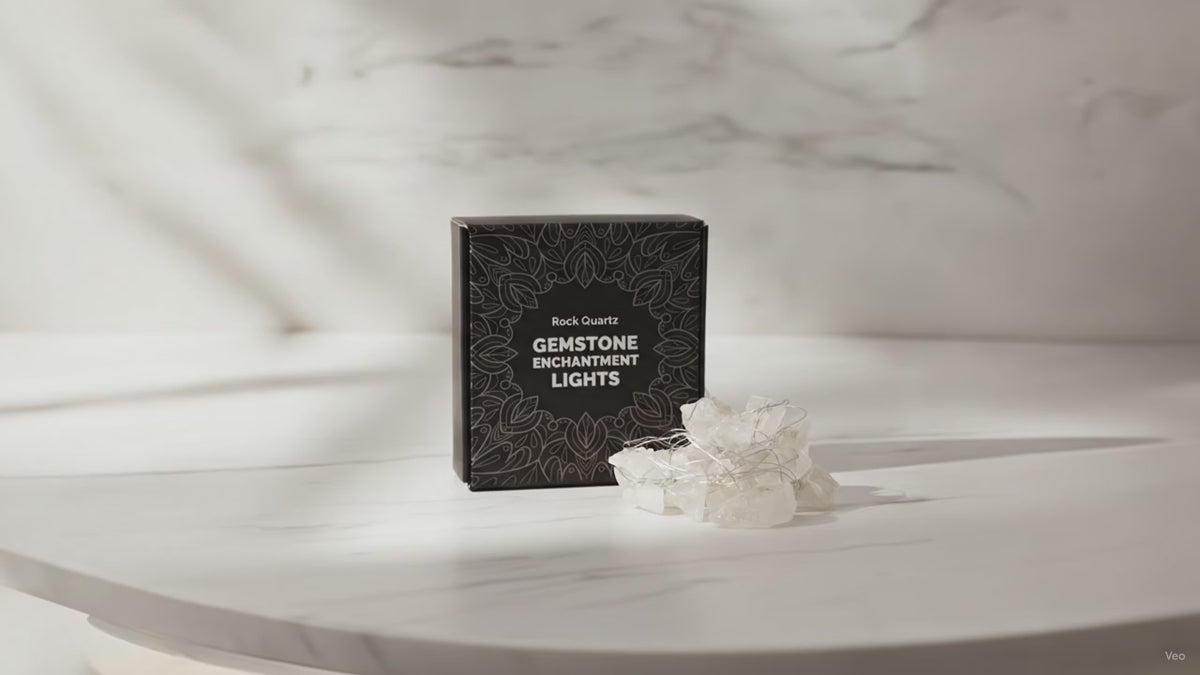 Clear quartz crystal fairy lights in their black gift box on a marble table, sunlight moving across the wall