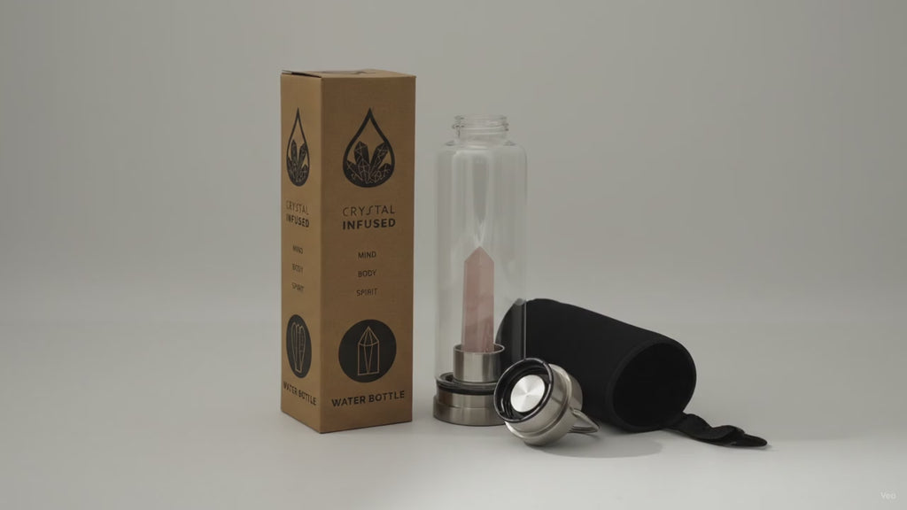 Rose quartz crystal water bottle with its box, lid and padded sleeve, soft light moving across the wall
