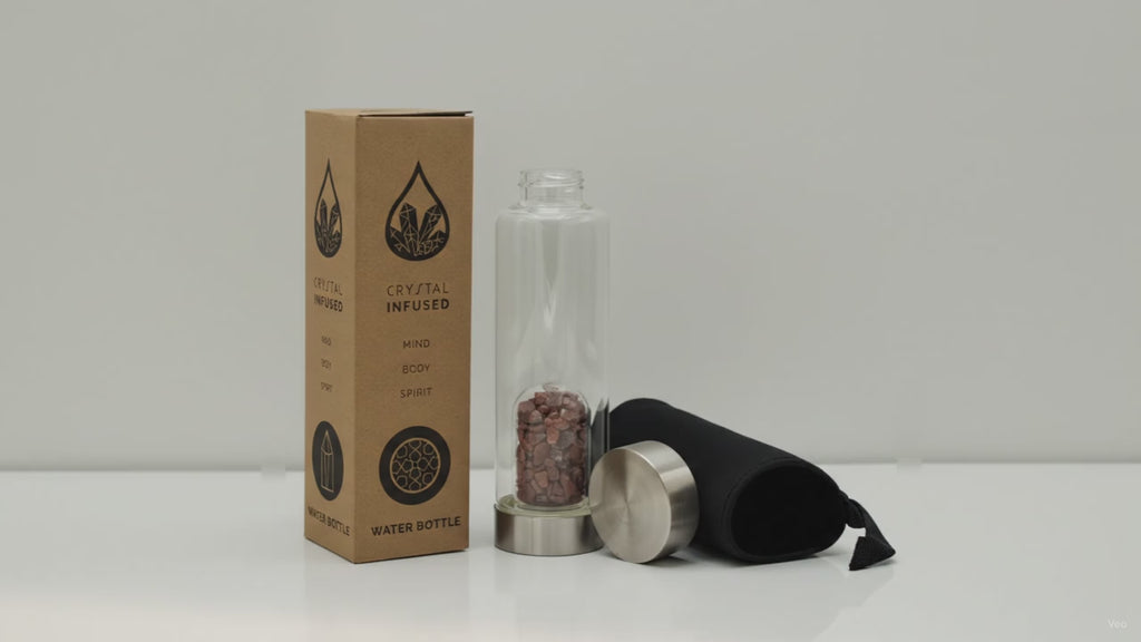 Red jasper chips crystal water bottle with its box, lid and padded sleeve, soft light moving across the wall