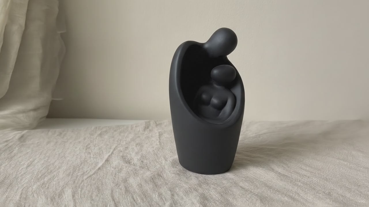 Matte black backflow burner shaped as two figures embracing, on rumpled linen video