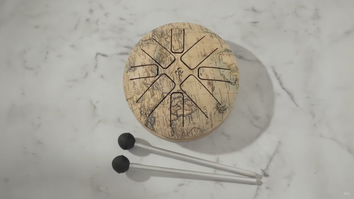 Small steel tongue drum in the Atlas world map design with two beaters, slow close-up