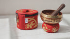 Mini brass singing bowl gift set in red with cushion, striker and carry case, slow camera push-in