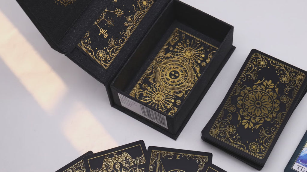 Gold foil tarot deck in its open gift box as warm window light moves across the table