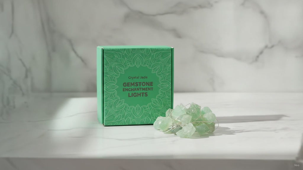 Green crystal jade fairy lights in their green gift box on a marble table, sunlight moving across the wall