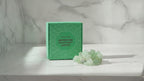 Green crystal jade fairy lights in their green gift box on a marble table, sunlight moving across the wall