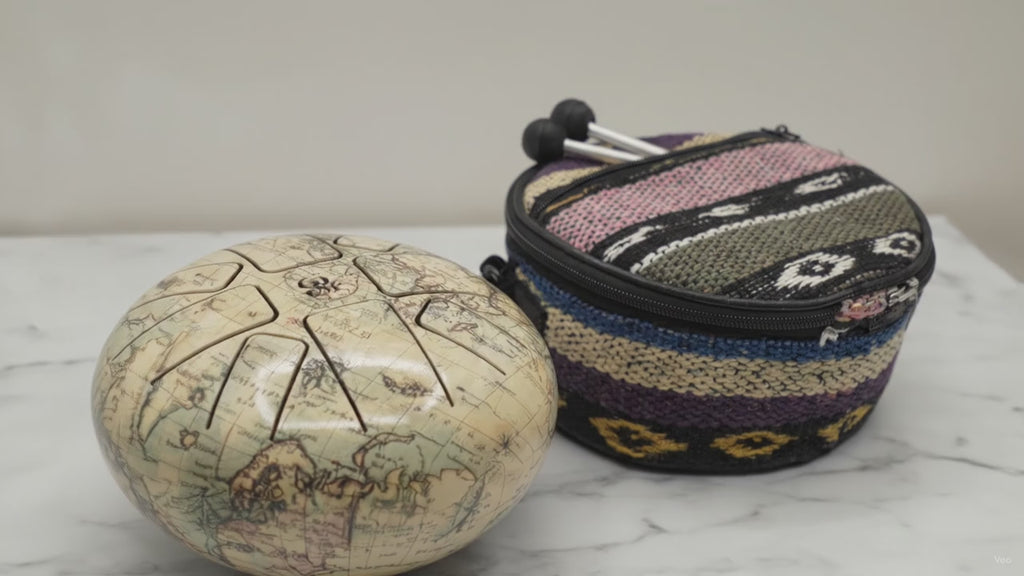 Medium Atlas steel tongue drum with its patterned carry bag on marble, slow camera push-in