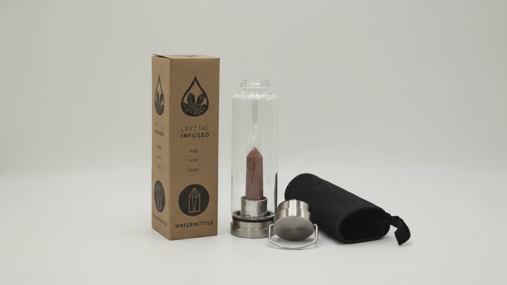 Red jasper crystal water bottle with its box, lid and padded sleeve, soft light moving across the wall