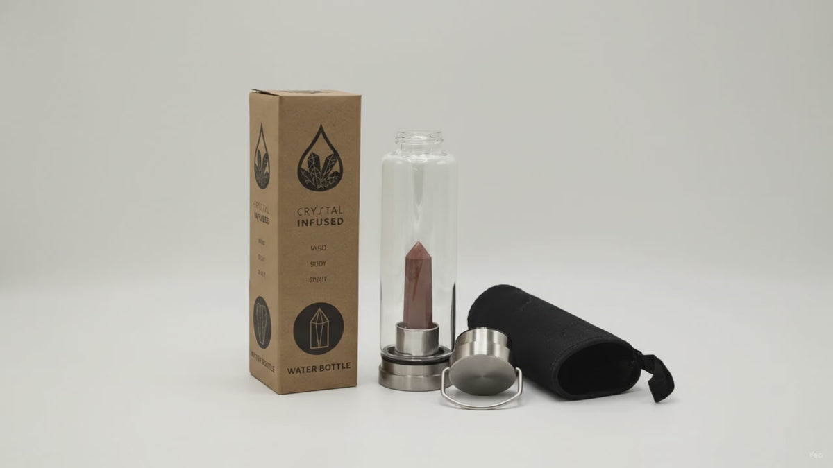 Red jasper crystal water bottle with its box, lid and padded sleeve, soft light moving across the wall