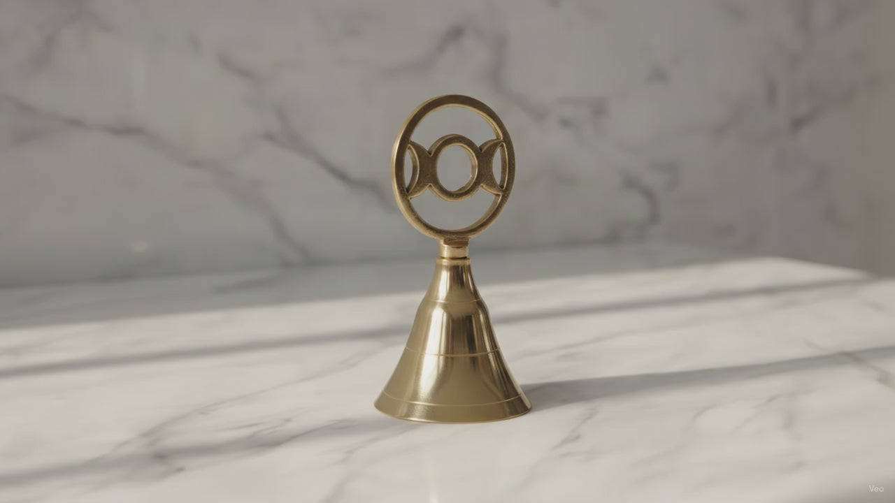 Triple moon brass altar bell on a marble table, slow product video