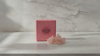 Rose quartz crystal fairy lights in their pink gift box on a marble table, sunlight moving across the wall