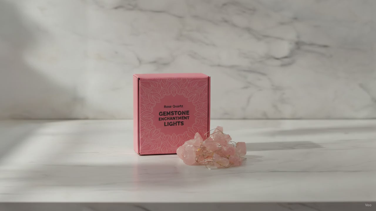 Rose quartz crystal fairy lights in their pink gift box on a marble table, sunlight moving across the wall