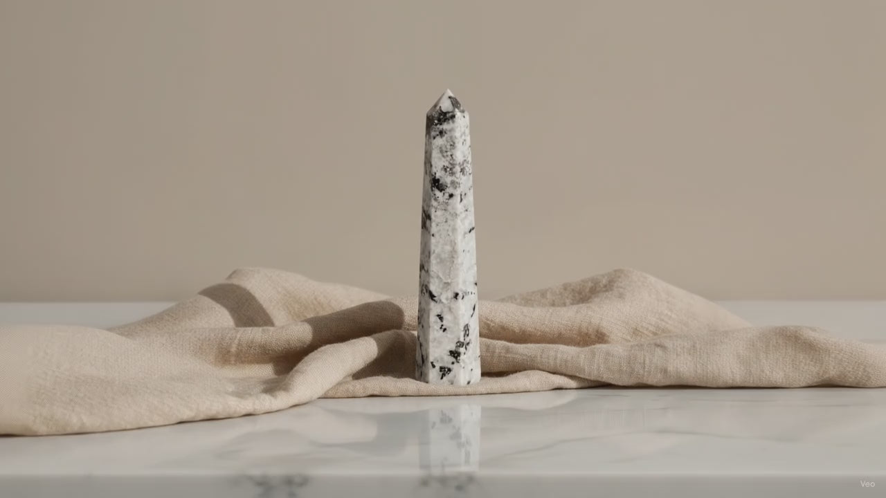 Rainbow moonstone crystal obelisk point on linen, slow zoom in