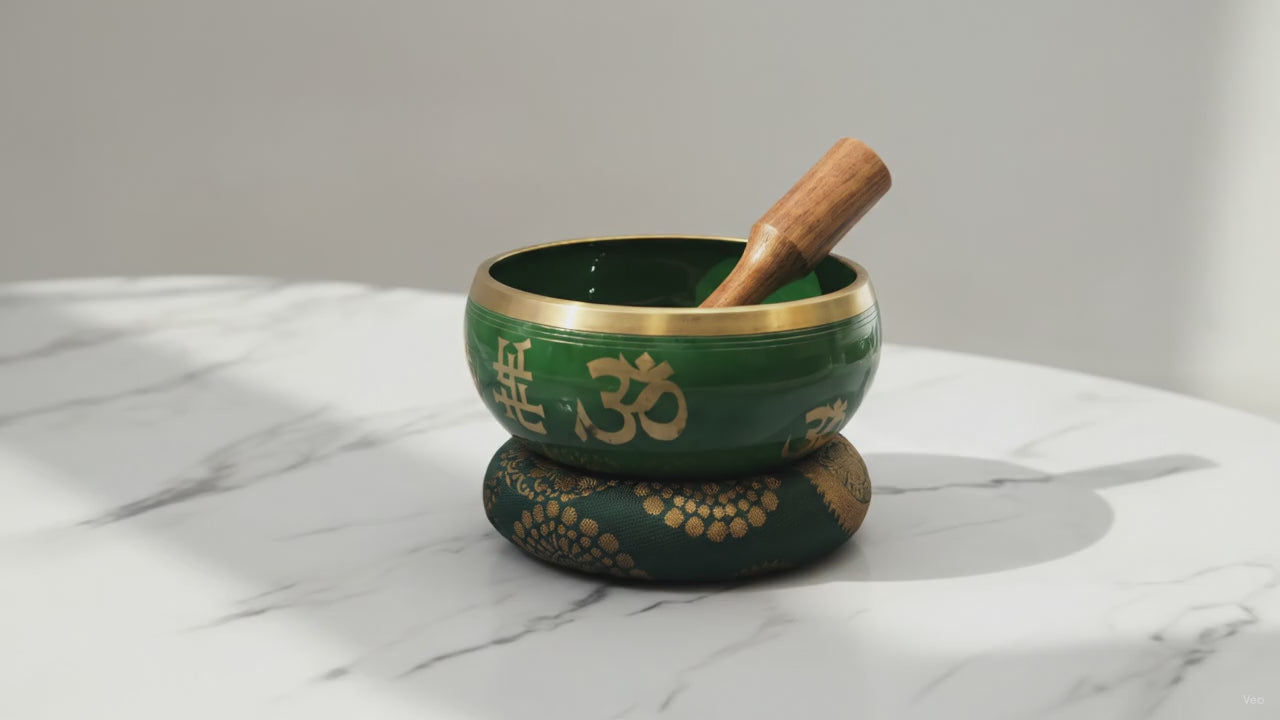 Large green singing bowl set with gold Tree of Life symbols, cushion and wooden striker on marble, slow push-in