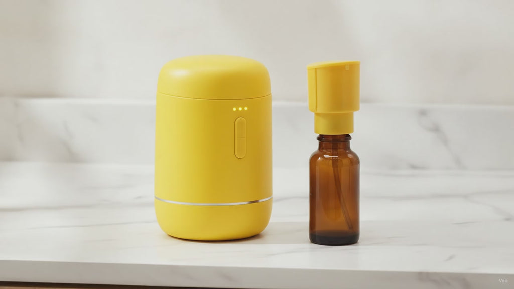 Yellow USB essential oil diffuser beside an amber oil bottle on a marble worktop, slow camera push-in