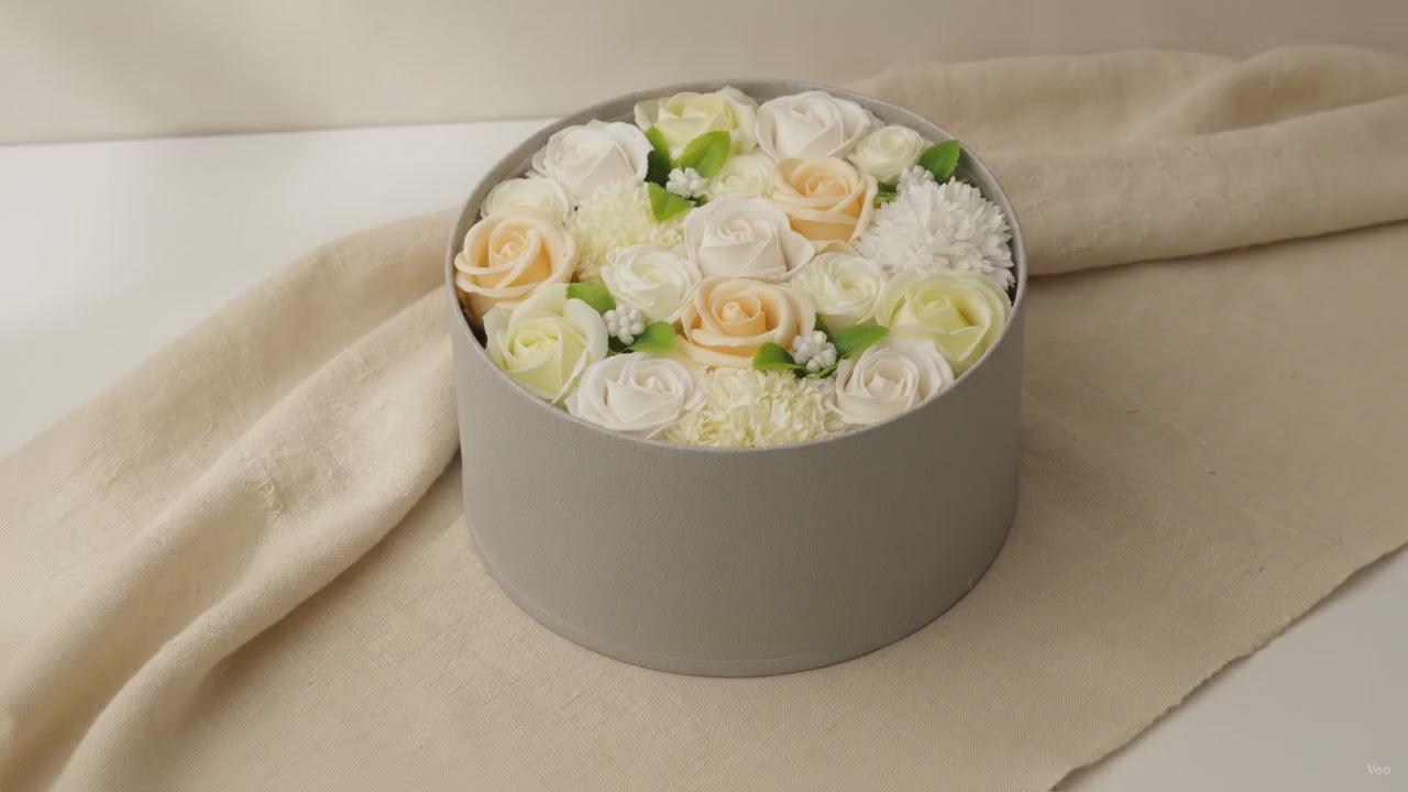 Round box packed with white and ivory soap roses, seen from above on cotton-rag paper video