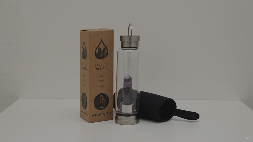 Amethyst crystal water bottle with its box and padded sleeve, sunlight moving across the wall