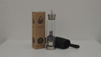 Amethyst crystal water bottle with its box and padded sleeve, sunlight moving across the wall