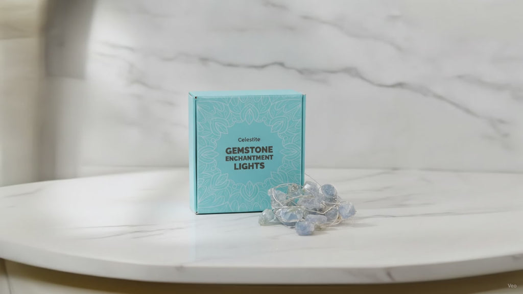 Celestite crystal fairy lights in their blue gift box on a marble table, sunlight moving across the wall