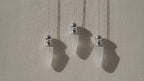 Three clear quartz pendulums with silver caps hanging from fine chains video