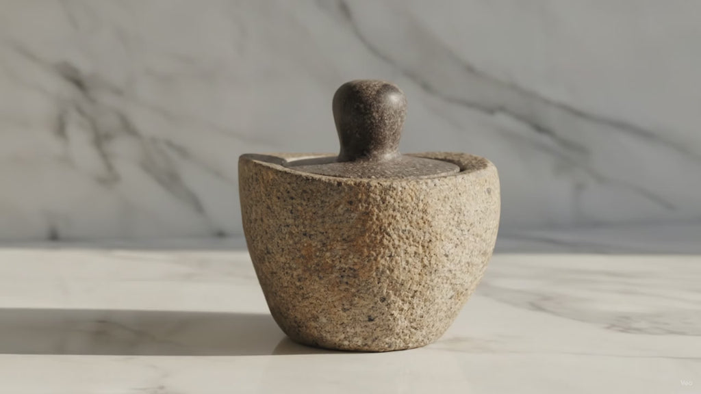Medium river stone pot with stone lid on a marble table, sunlight moving across the wall