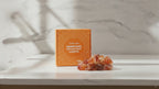 Orange jade crystal fairy lights in their orange gift box on a marble table, sunlight moving across the wall