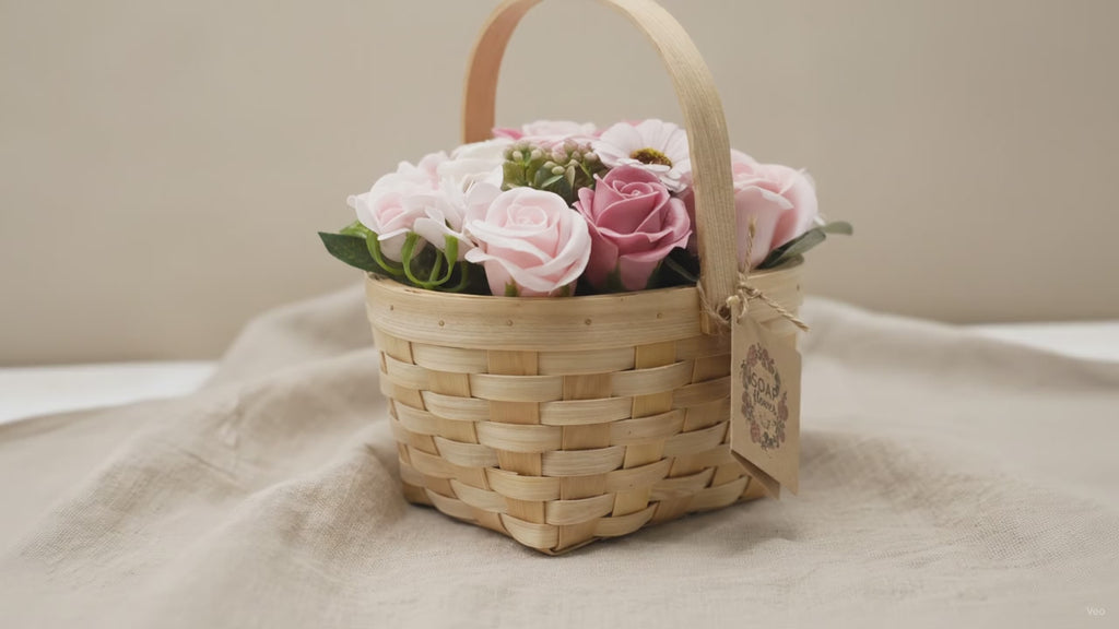 Pink and blush soap roses in a woven wicker basket with a tag, on rumpled linen video