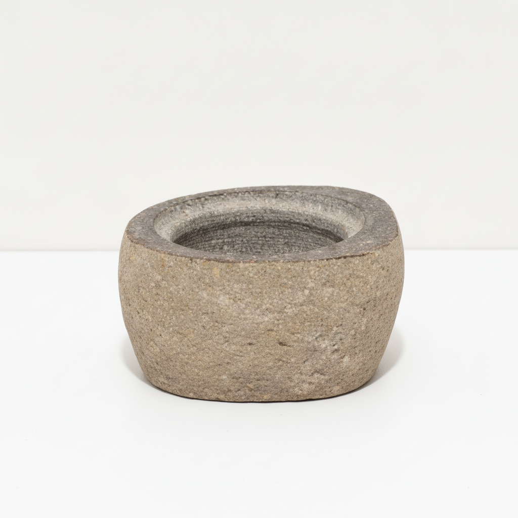 Small river stone pot with stone lid on a clean white surface against a white wall