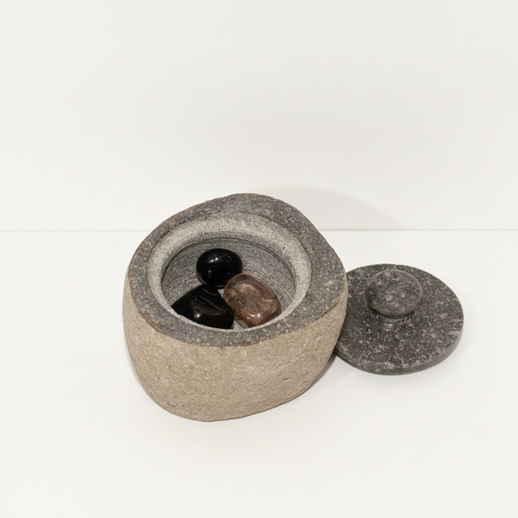 Small river stone pot with stone lid on a clean white surface against a white wall