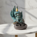 Skull in hand backflow incense burner on a marble table with a marble wall behind