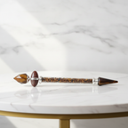 Tiger eye shiva lingam wand on a marble table with a marble wall behind