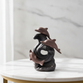 Dolphin wave backflow incense burner on a marble table with a marble wall behind
