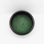 Earth powder singing bowl with mandala buddha on a clean white surface against a white wall