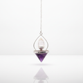 Amethyst and rock quartz lantern of life pendulum on a clean white surface against a white wall