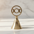 Triple moon brass altar bell on a marble table with a marble wall behind