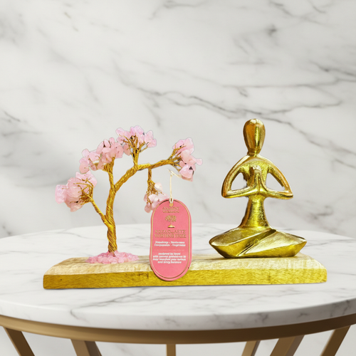 Rose quartz gemstone yoga garden with brass namaste figure on a marble table