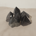 Polished black tourmaline crystal points grouped together on natural linen