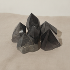 Polished black tourmaline crystal points grouped together on natural linen