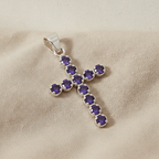 Silver-plated crucifix pendant set with deep purple stones, on linen