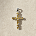 Silver-plated crucifix pendant set with golden citrine-coloured stones, on linen