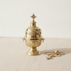 Ornate brass hanging incense burner standing on its footed base, chains beside it