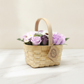 Lilac and purple soap roses in a woven wicker basket with a tag, on cotton-rag paper