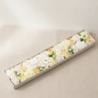 Long box of white and ivory soap roses lying open on cotton canvas