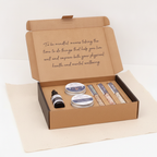 Kraft self-care kit box open flat, showing scrub tins, serum bottle and bath salt tubes