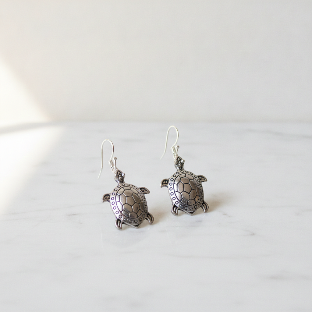 A pair of sterling silver turtle drop earrings on cotton canvas - view 2