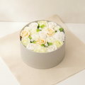 Round box packed with white and ivory soap roses, seen from above on cotton-rag paper